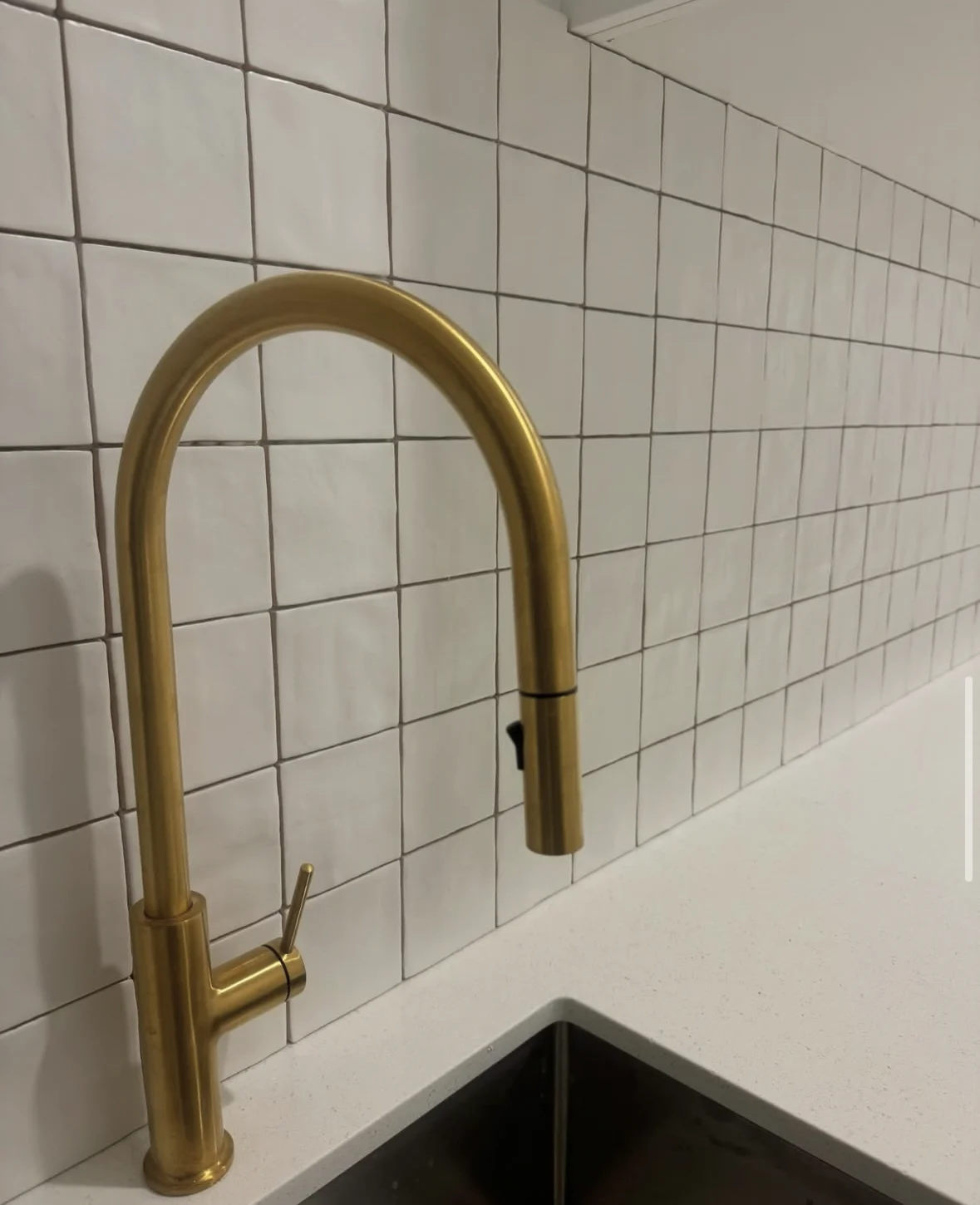Small white handmade splashback tiles with a brushed brass kitchen tap