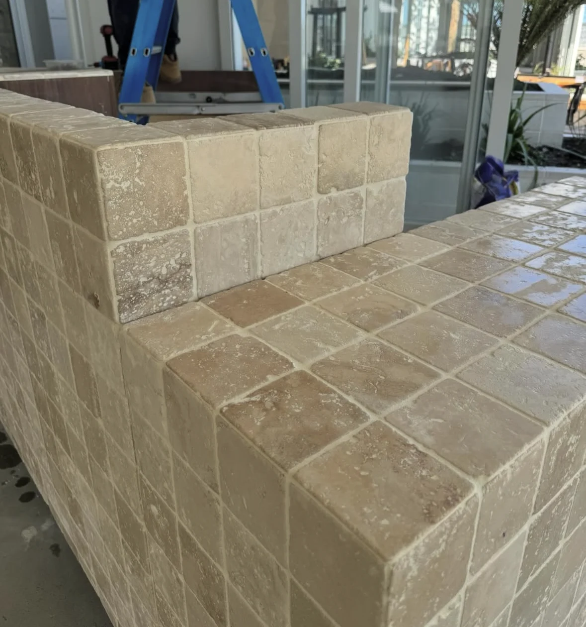 Close view of travertine tiles wrapping a restaurant counter during installation